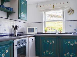 a kitchen with green cabinets and a sink and a window at Vindolanda in Fearnmore