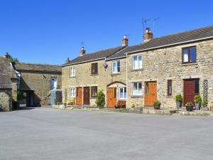a row of stone houses with orange doors on a street at Crown Courtyard Cottage in Grewelthorpe