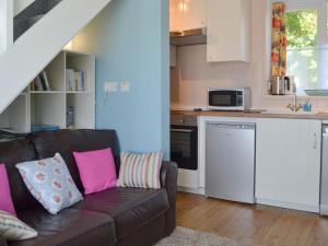 a living room with a couch and a kitchen at Crown Courtyard Cottage in Grewelthorpe