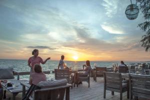 a group of people sitting at a restaurant on the beach at Mango Bay Resort in Phu Quoc