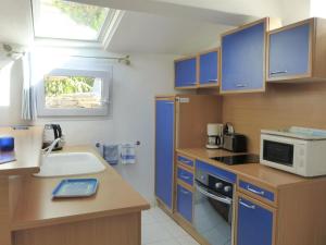 cocina con armarios azules, fregadero y microondas en Semi-detached house, Pégomas en Pégomas