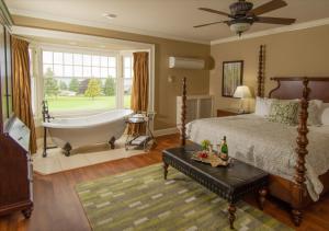 Schlafzimmer mit einem Bett, einer Badewanne und einem Fenster in der Unterkunft Crown Mansion Boutique Hotel & Villas in Qualicum Beach