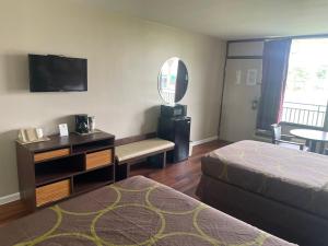 a hotel room with a bed and a desk and a television at Super 8 by Wyndham Valdosta Mall in Valdosta