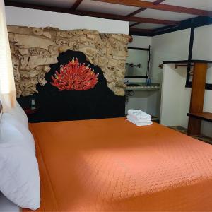 a bedroom with a large orange bed with a stone wall at Hotel Caba&ntilde;as Safari in Palenque
