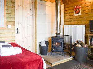 a bedroom with a stove and a bed with a red blanket at Robins Lodge in Westward