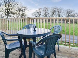 una mesa y sillas en una terraza con una valla en Robins Lodge en Westward