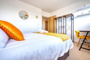 a bedroom with a bed with an orange pillow on it at Stylish 2 bed flat in Basingstoke By 20Property Stays Short Lets & Serviced Accommodation in Basingstoke