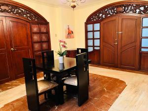 una sala da pranzo con tavolo, sedie e porte in legno di Mega Suite junto al San Marino Shopping a Guayaquil