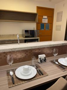 uma cozinha com uma mesa com pratos e copos de vinho em Flat Rio Centro - Jeunesse Arena - Barra da Tijuca - Projac - TV Globo - Parque dos Atletas no Rio de Janeiro