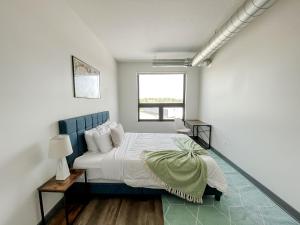 a bedroom with a bed with a blue headboard and a window at Sleepover 1BD 1BA Des Moines Apartments in Des Moines