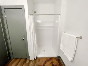a bathroom with a shower with a towel and a door at Sleepover 1BD 1BA Des Moines Apartments in Des Moines