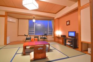 a living room with a table and a tv at Nikko Tokinoyuu in Nikko