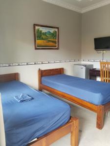 a bedroom with two beds and a television in it at Jepun Segara Guest House in Kuta