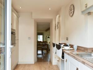 a kitchen with white cabinets and a dining room at Easter Cottage in Bamford