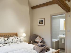 a bedroom with a bed and a chair and a sink at Easter Cottage in Bamford