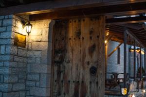 una puerta de madera en una pared de ladrillo con una luz en Arkefthos Mountain Hotel en Papigo