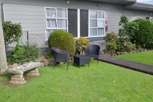 a yard with two chairs and a bench in front of a house at Rockfield Motel in Auckland