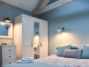 a bedroom with blue walls and a bed and a cabinet at Primrose in Scruton