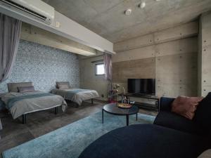 salon z 2 łóżkami i telewizorem w obiekcie La luna w mieście Yomitan