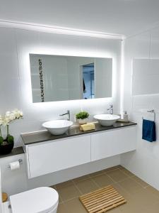 a white bathroom with two sinks and a mirror at Belle by the Bay in Fingal Bay
