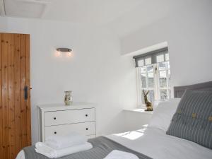 a bedroom with a bed and a dresser and a window at Lavender Cottage in Leyburn