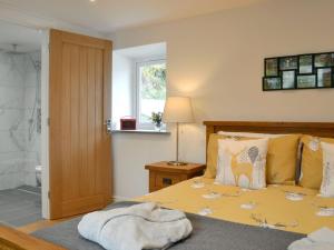 a bedroom with a bed and a window and a bathroom at Ladyvale Barn in Cardinham