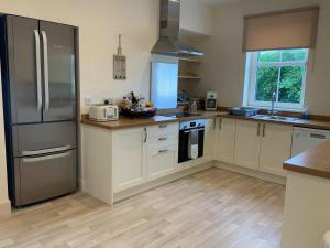 a kitchen with white cabinets and a stainless steel refrigerator at Balmore Farmhouse in Lochend