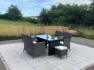 a patio with a table and chairs and a bench at Balmore Farmhouse in Lochend