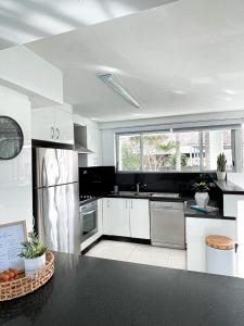 a kitchen with white cabinets and a large window at Belle by the Bay in Fingal Bay