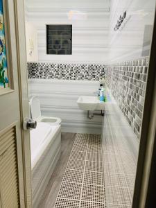 La salle de bains est pourvue d'une baignoire, d'un lavabo et de toilettes. dans l'établissement Holiday House near Butuan City Airport, à Butuan