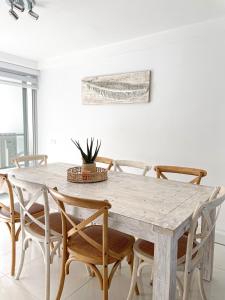 a white dining room with a wooden table and chairs at Belle by the Bay in Fingal Bay