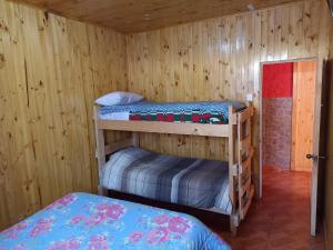 Ce lit se trouve dans un dortoir doté de 2 lits superposés et de murs en bois. dans l'établissement Cabañas Don Fernando, à Laguna Verde