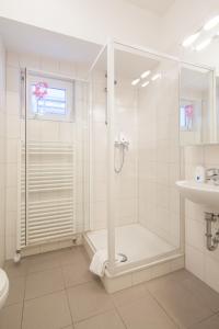 ein weißes Bad mit einer Dusche und einem Waschbecken in der Unterkunft Hotel Herzog in Düsseldorf