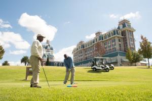 zwei Männer, die vor einem großen Gebäude Golf spielen in der Unterkunft Walmont at Graceland in Secunda