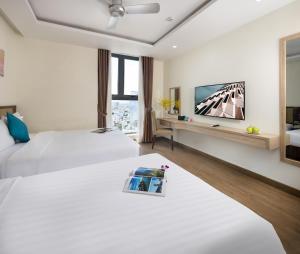 a hotel room with two beds and a flat screen tv at Sata Hotel in Nha Trang