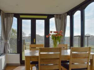 a dining room with a table and chairs and windows at Woodpeckers in Herstmonceux