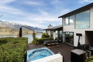 una casa con bañera de hidromasaje en una terraza en Luxury Lake View Retreat with Hot Tub en Queenstown