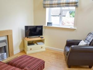 uma sala de estar com um sofá e uma televisão numa mesa em Eagles Cottage em Corston