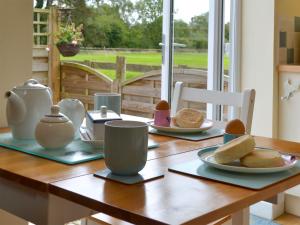uma mesa de madeira com pratos de ovos e pão em Eagles Cottage em Corston