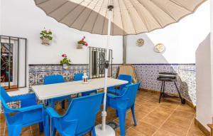 jadalnia ze stołem, niebieskimi krzesłami i parasolem w obiekcie Gorgeous Home In Mlaga With Wifi w Maladze