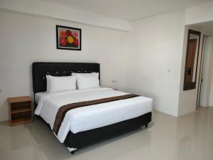 a bedroom with a large bed with white sheets at Golden Ganesha Hotel Yogyakarta by Ecommerceloka in Gondowulung