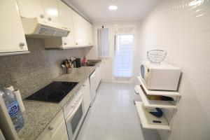 cocina blanca con microondas y fogones en Jávea Golden Beach 1 Arenal Beach, en Jávea