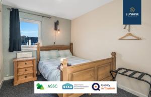 a bedroom with a wooden bed and a window at THE LAW, 4 Rooms with TVs, 2 Bathrooms, Central, Free Parking, Fully Equipped, Long Stay Rates Available visit SUNRISE SHORT LETS in Dundee