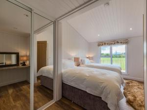 a white bedroom with two beds and a mirror at Karelia Lodge in Kenmore