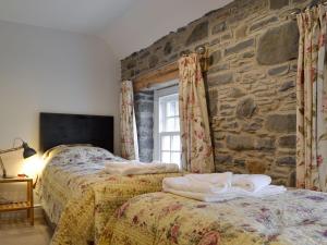 een slaapkamer met 2 bedden en een stenen muur bij The Mill in Tregaron