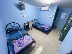 a blue room with two beds and a table at Ikhlas Roomstay in Kampong Alor Gajah