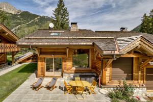 a log cabin with a table and chairs on a patio at La Cloche des Bois - Alpes Travel - Les Bois - Sleeps 4-6 in Chamonix-Mont-Blanc