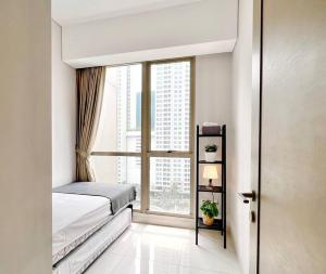 een slaapkamer met een bed en een groot raam bij Cozy 3BR Suite at TA Residence in Jakarta