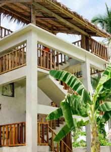 a house with a wooden balcony and a palm tree at Diwa Siargao Eco-House in General Luna