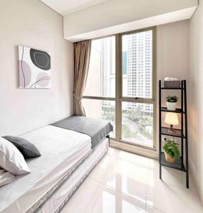 ein Schlafzimmer mit einem Bett und einem großen Fenster in der Unterkunft Comfy 3 BR at TA Residence in Jakarta